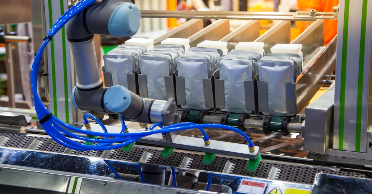 A machine with blue wires coming off it. There are rows of products in sealed pouches being prepared for distribution.