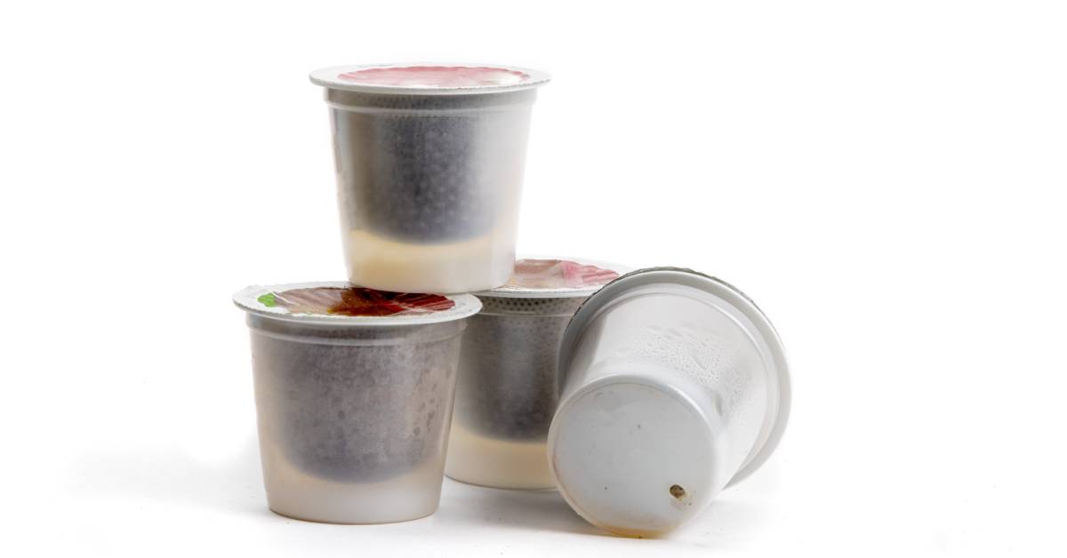 A group of four single-serve coffee pods against a white background. One pod has a hole in the bottom, indicating it was used.